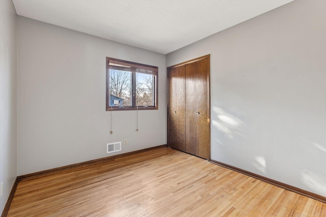 unfurnished bedroom with visible vents, baseboards, a closet, and light wood finished floors