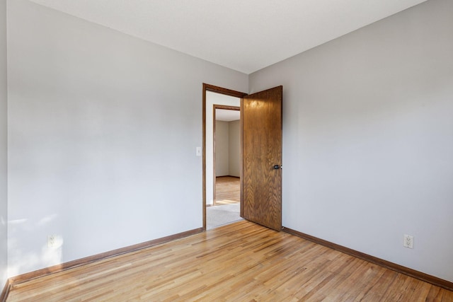 spare room with baseboards and light wood-style floors