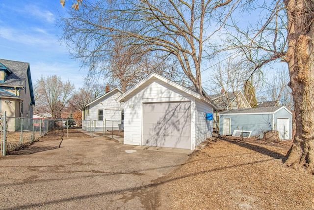 view of outbuilding with a garage, an outbuilding, concrete driveway, and fence