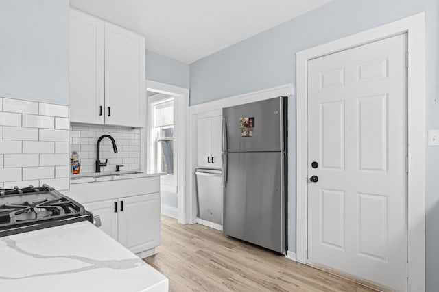 kitchen featuring white cabinets, freestanding refrigerator, light wood-style floors, and a sink