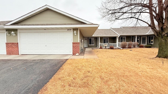 single story home with aphalt driveway, covered porch, a shingled roof, a garage, and brick siding