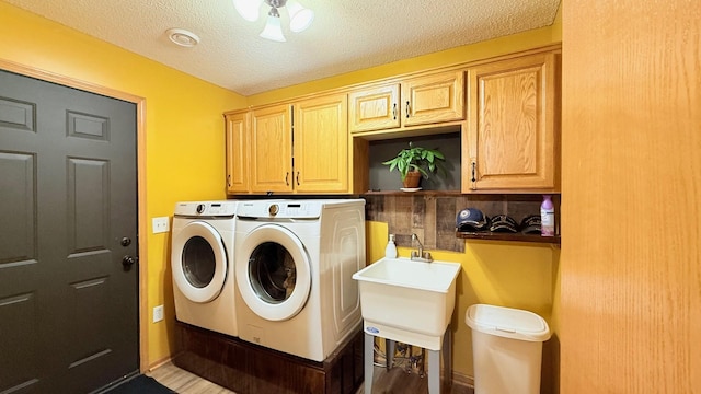 washroom with cabinet space, independent washer and dryer, and a textured ceiling