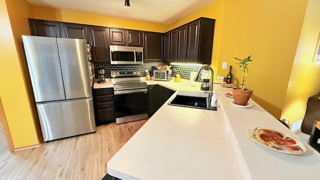 kitchen featuring a sink, light countertops, decorative backsplash, and stainless steel appliances