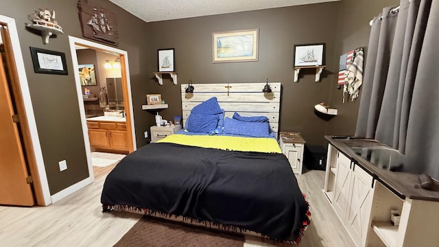 bedroom with light wood finished floors, a textured ceiling, and ensuite bath