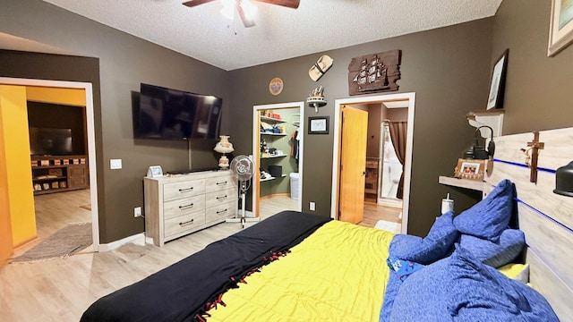 bedroom with a ceiling fan, wood finished floors, baseboards, a textured ceiling, and connected bathroom