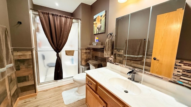 bathroom featuring wood finished floors, toilet, a stall shower, and vanity