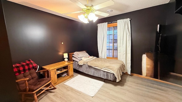 bedroom with a textured ceiling, a ceiling fan, and wood finished floors