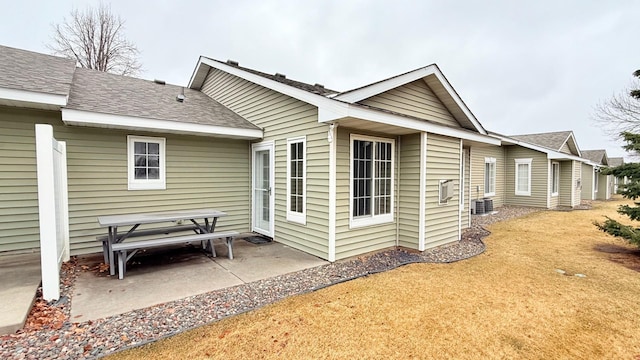 rear view of property with cooling unit, a patio area, and roof with shingles