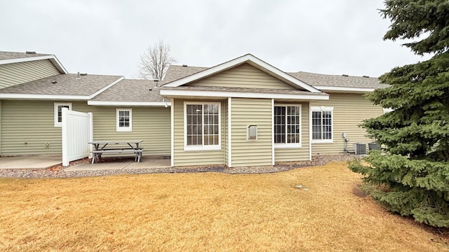 rear view of property featuring a yard, a shingled roof, and a patio