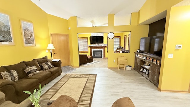 living room with a glass covered fireplace, light wood-style floors, and baseboards