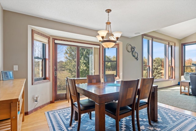 dining room featuring baseboards, light wood-type flooring, a chandelier, and a textured ceiling