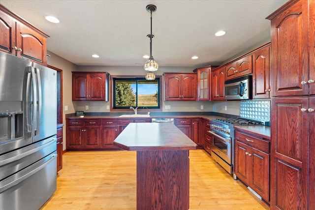 kitchen with light wood finished floors, decorative light fixtures, recessed lighting, appliances with stainless steel finishes, and a sink