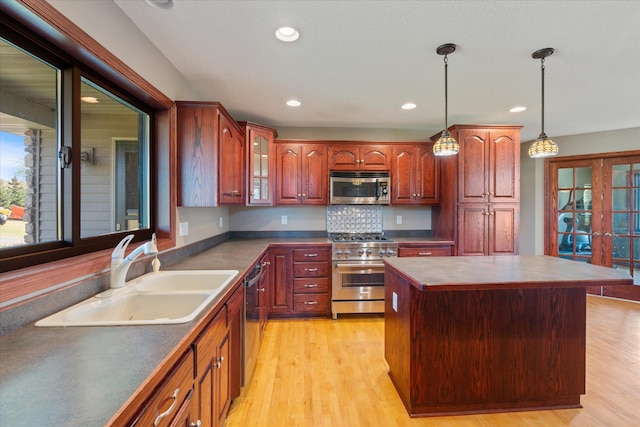 kitchen with a sink, dark countertops, light wood finished floors, and stainless steel appliances