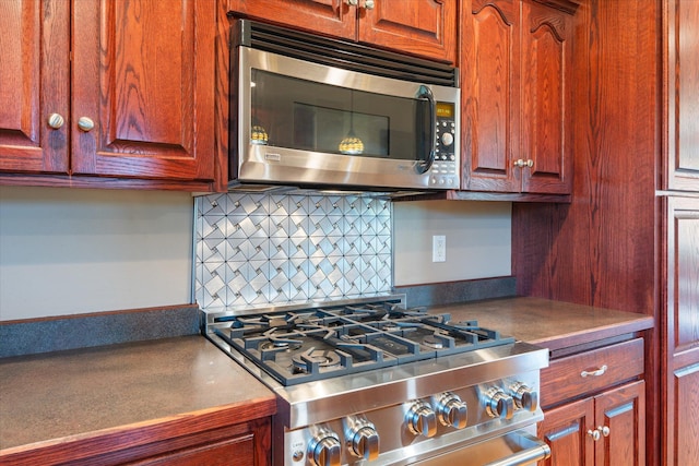 kitchen featuring stainless steel microwave, gas range, and backsplash