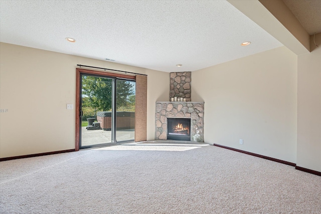 unfurnished living room featuring a fireplace, a textured ceiling, baseboards, and carpet floors