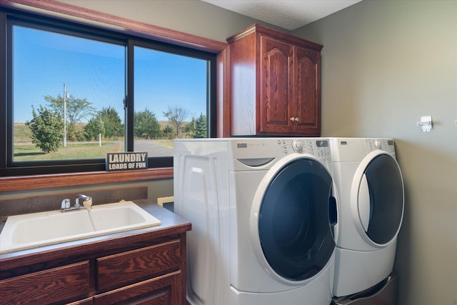 clothes washing area featuring a sink, cabinet space, and washer and dryer