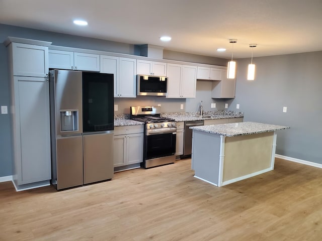 kitchen featuring a kitchen island, recessed lighting, light wood-style floors, stainless steel appliances, and a sink