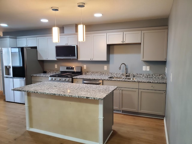 kitchen featuring light wood-style flooring, a kitchen island, appliances with stainless steel finishes, and a sink