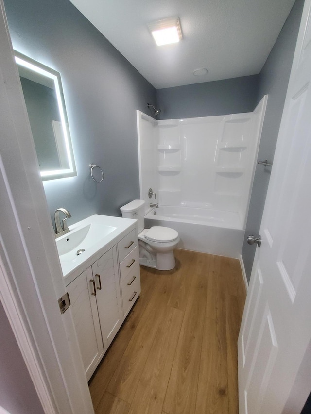 bathroom featuring vanity, toilet, wood finished floors, and shower / bathtub combination