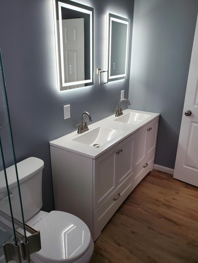 bathroom featuring double vanity, toilet, wood finished floors, and a sink