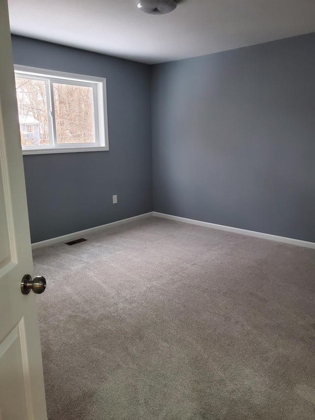 carpeted spare room with visible vents and baseboards