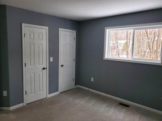 unfurnished bedroom featuring baseboards, visible vents, and carpet floors