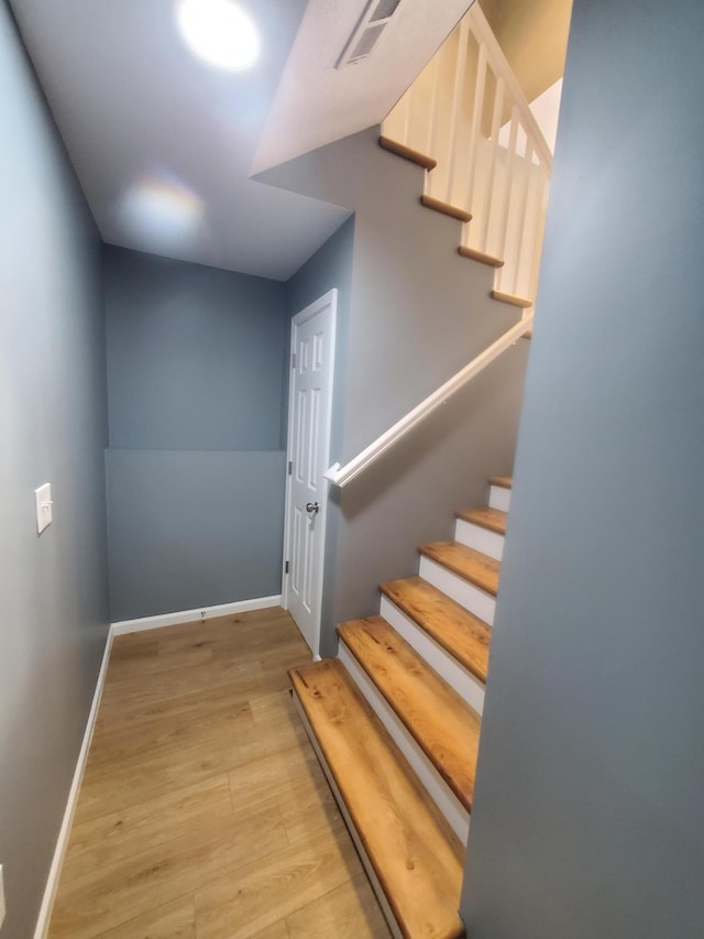 staircase with visible vents, baseboards, and wood finished floors