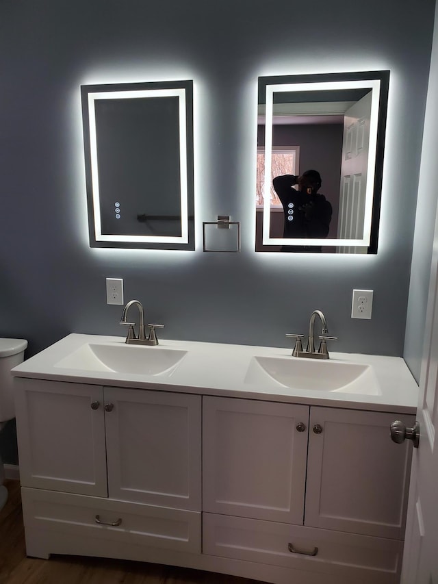 bathroom featuring double vanity, toilet, and a sink