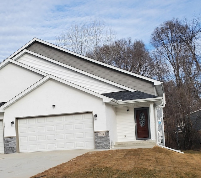 view of front facade with stone siding, a garage, driveway, and stucco siding