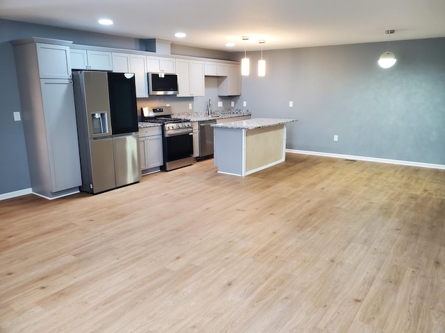 kitchen featuring light wood finished floors, baseboards, appliances with stainless steel finishes, and a kitchen island