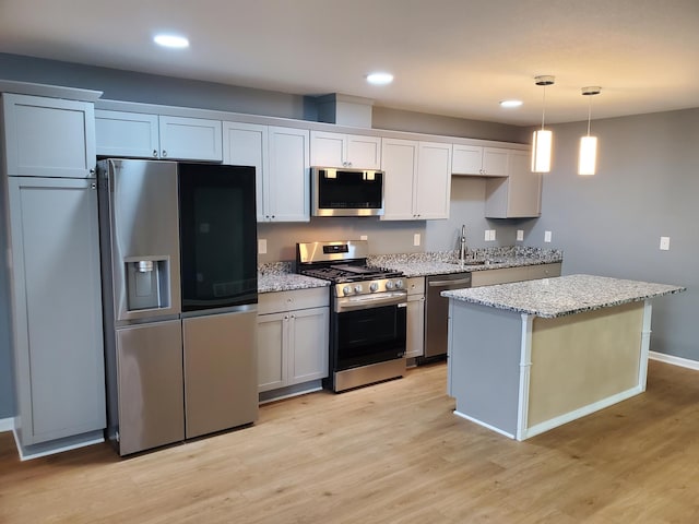 kitchen with a sink, stainless steel appliances, light wood-style flooring, and a center island