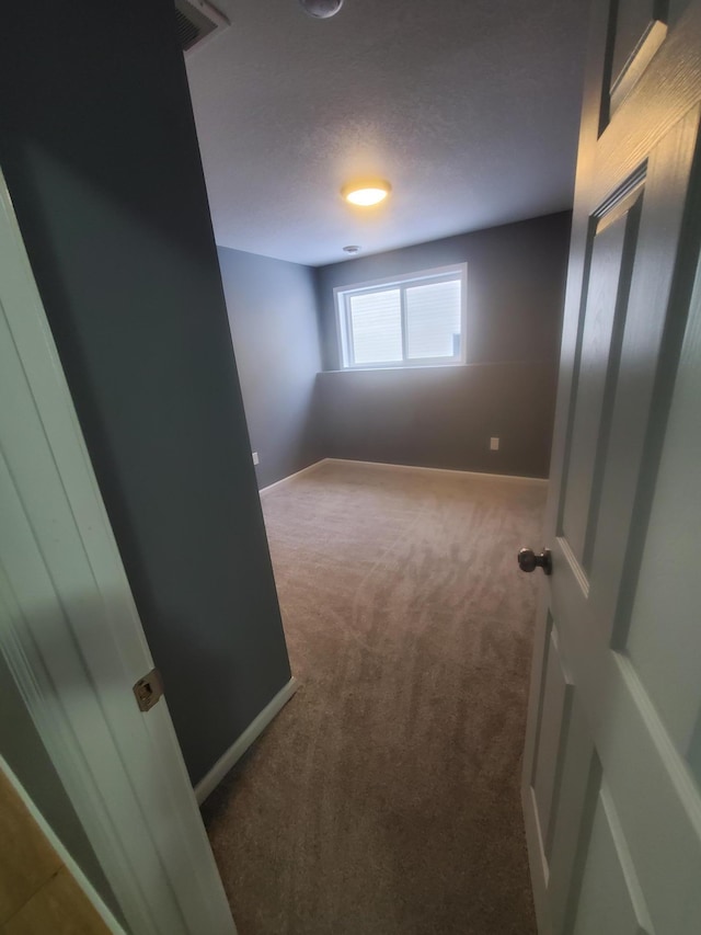 carpeted spare room featuring visible vents, baseboards, and a textured ceiling