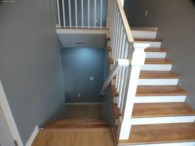 staircase featuring visible vents, baseboards, and wood finished floors