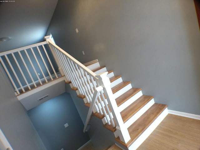 stairway featuring wood finished floors, visible vents, and baseboards