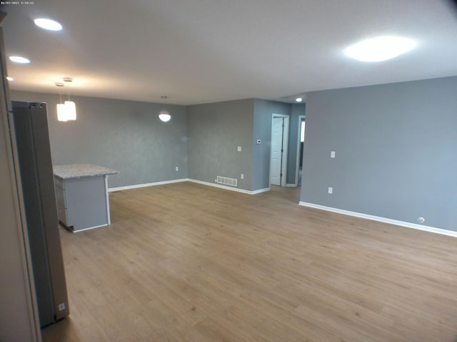 unfurnished living room featuring light wood-style floors, visible vents, and baseboards