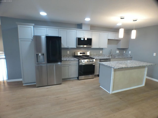 kitchen with light wood-style flooring, appliances with stainless steel finishes, a center island, and a sink