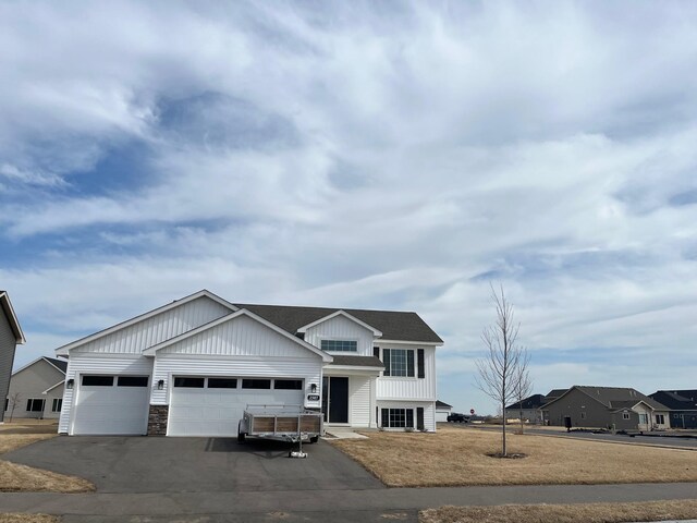 view of front of house with aphalt driveway, stone siding, board and batten siding, and a garage