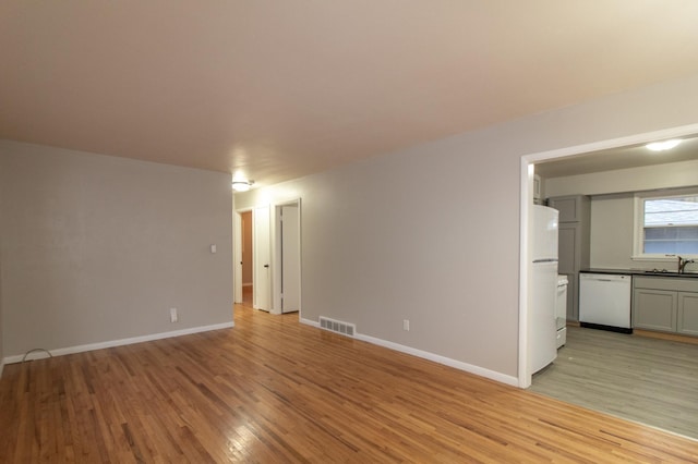 spare room featuring light wood-type flooring, baseboards, visible vents, and a sink