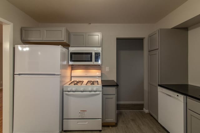 kitchen featuring white appliances, light wood-style floors, dark countertops, and gray cabinets