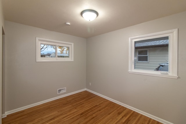 empty room featuring visible vents, baseboards, and wood finished floors