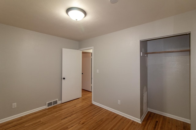 unfurnished bedroom featuring light wood-style flooring, baseboards, visible vents, and a closet