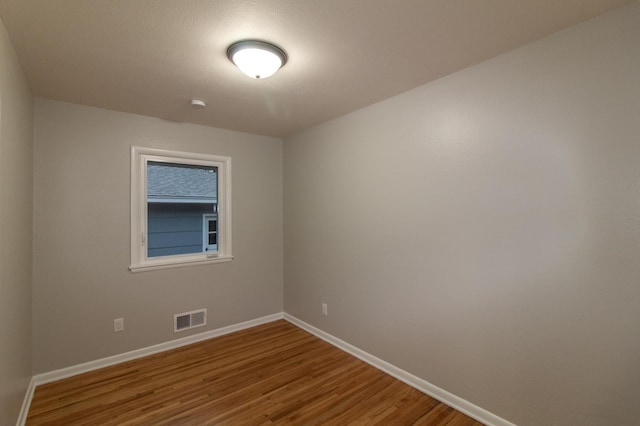 empty room with visible vents, baseboards, and wood finished floors