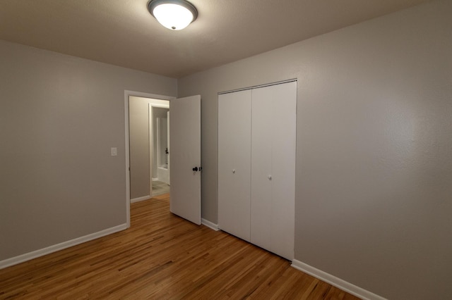 unfurnished bedroom with a closet, baseboards, and wood finished floors