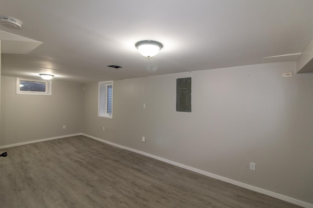 finished basement featuring dark wood finished floors, electric panel, and baseboards