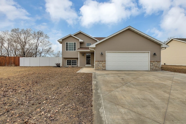 view of front facade featuring an attached garage, fence, stone siding, and driveway