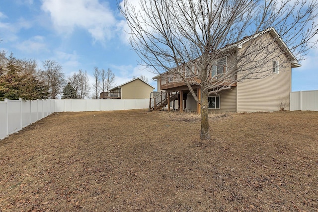 view of yard with a deck, a fenced backyard, and stairs