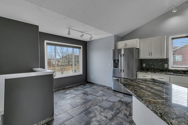 kitchen featuring plenty of natural light, vaulted ceiling, stainless steel fridge with ice dispenser, and white cabinetry