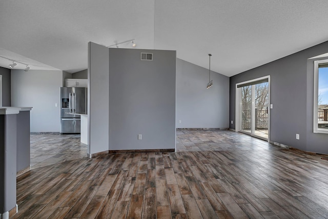 interior space featuring dark wood finished floors, visible vents, a textured ceiling, and vaulted ceiling