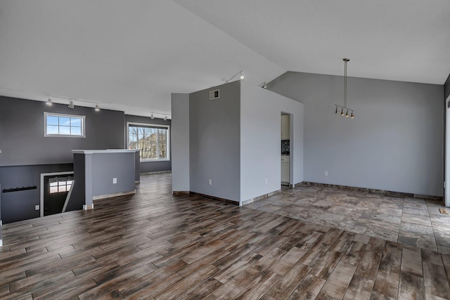 unfurnished living room with visible vents, track lighting, baseboards, lofted ceiling, and wood finished floors