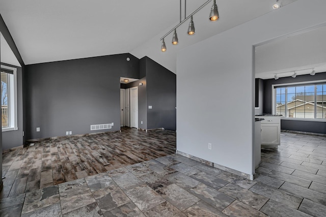 unfurnished room featuring visible vents, track lighting, lofted ceiling, and wood finished floors